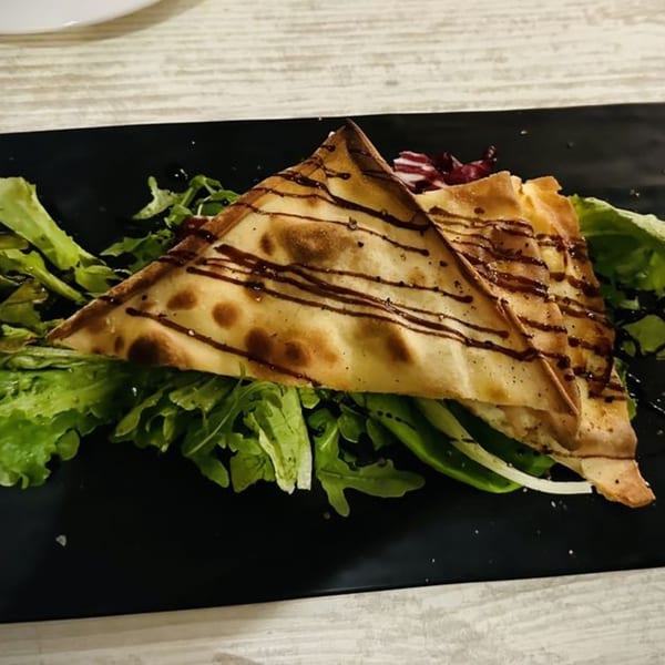 Italian flatbread triangles drizzled with balsamic glaze, served on a bed of fresh green salad.