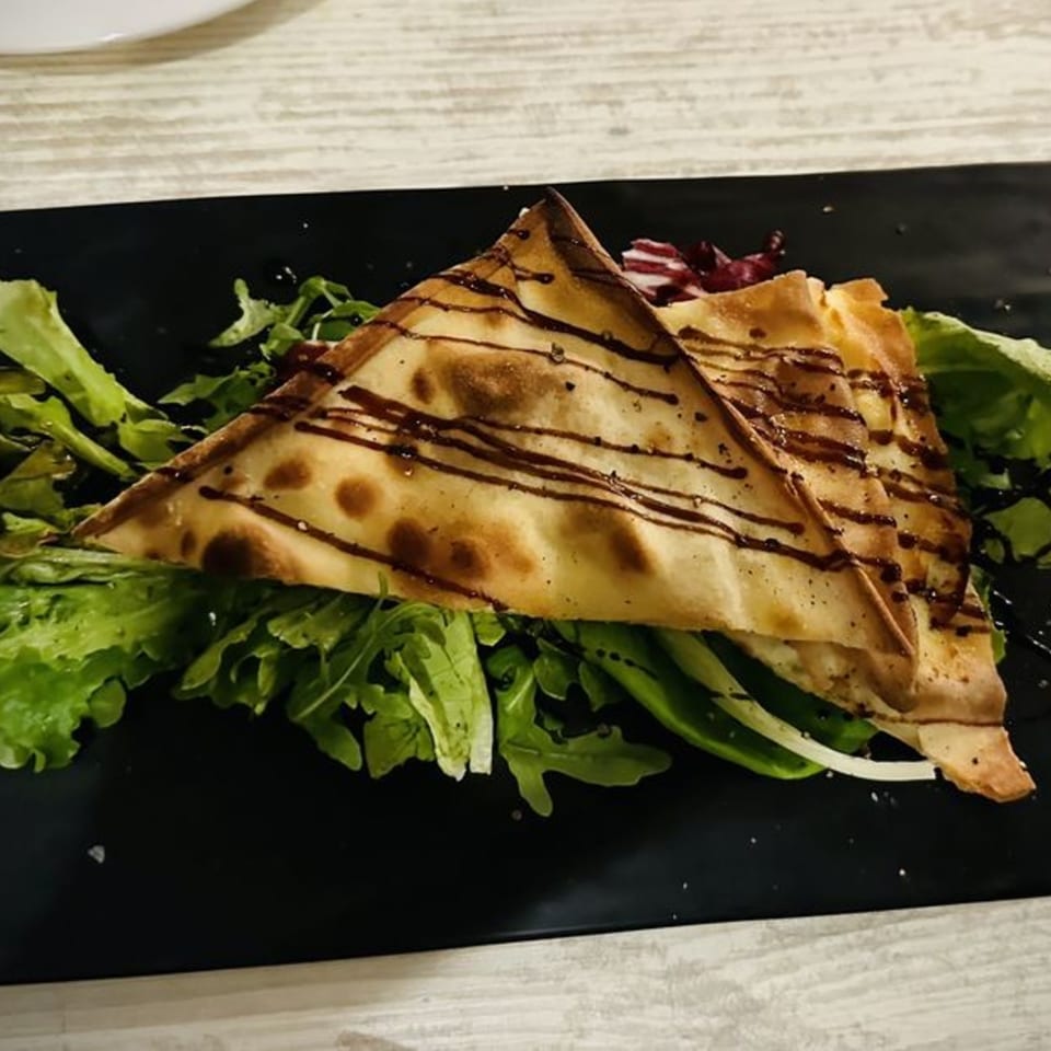 Italian flatbread triangles drizzled with balsamic glaze, served on a bed of fresh green salad.