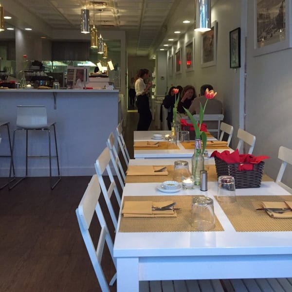 Interior of From Scratch, an Italian restaurant, with set tables, a bar area, and diners.