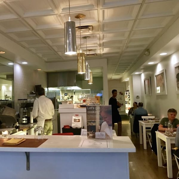 From Scratch Italian restaurant interior with a chef in the kitchen and patrons dining at tables.