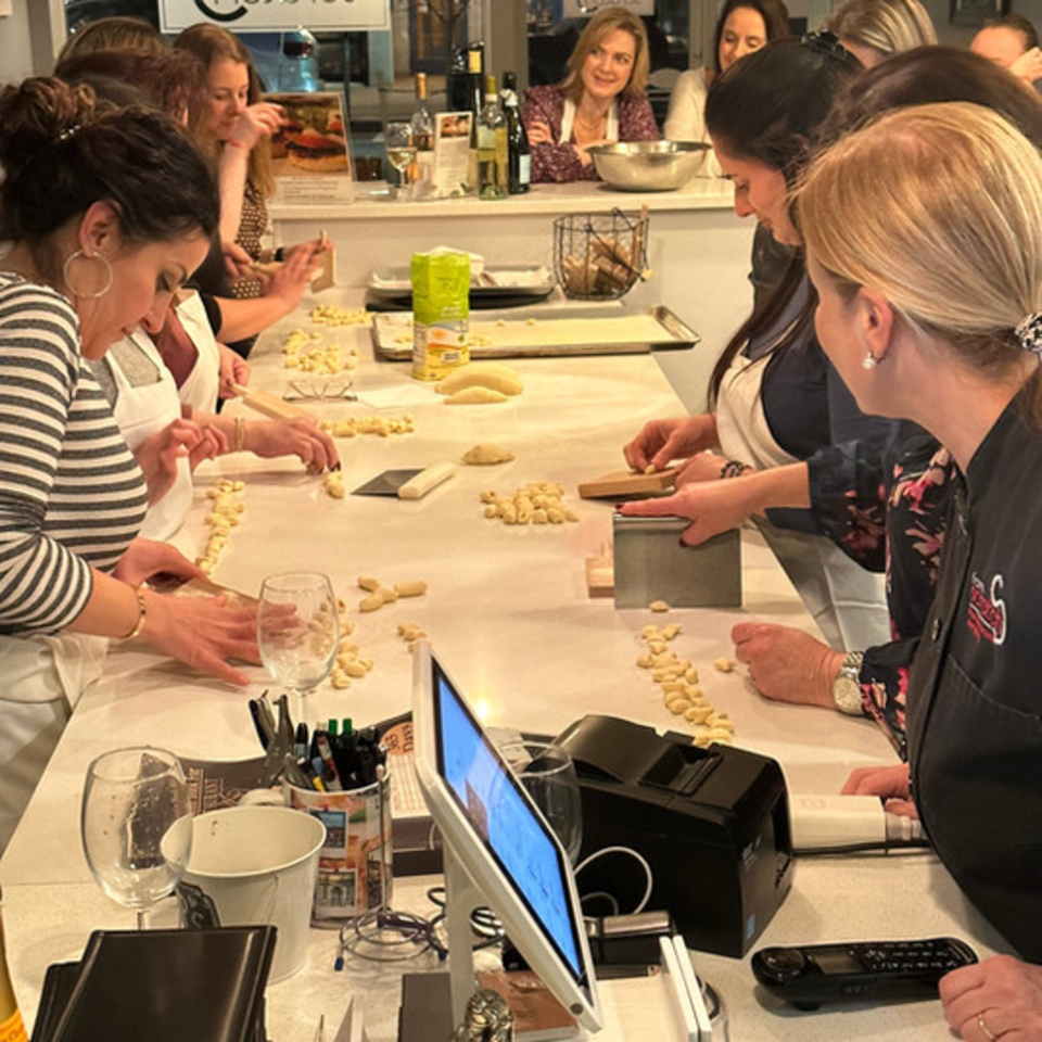 Women in aprons making fresh gnocchi by hand at an Italian cooking class.